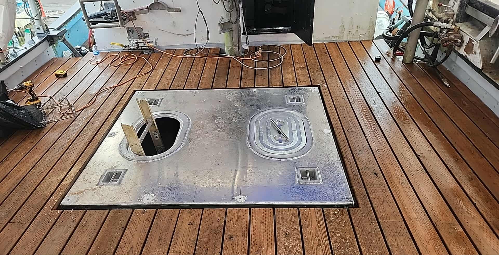 Custom aluminum deck plates and watertight hatches set into a teak working deck